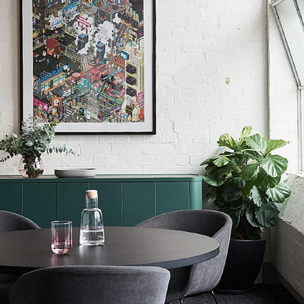 Modern interior with a cityscape painting, round table, and chairs.