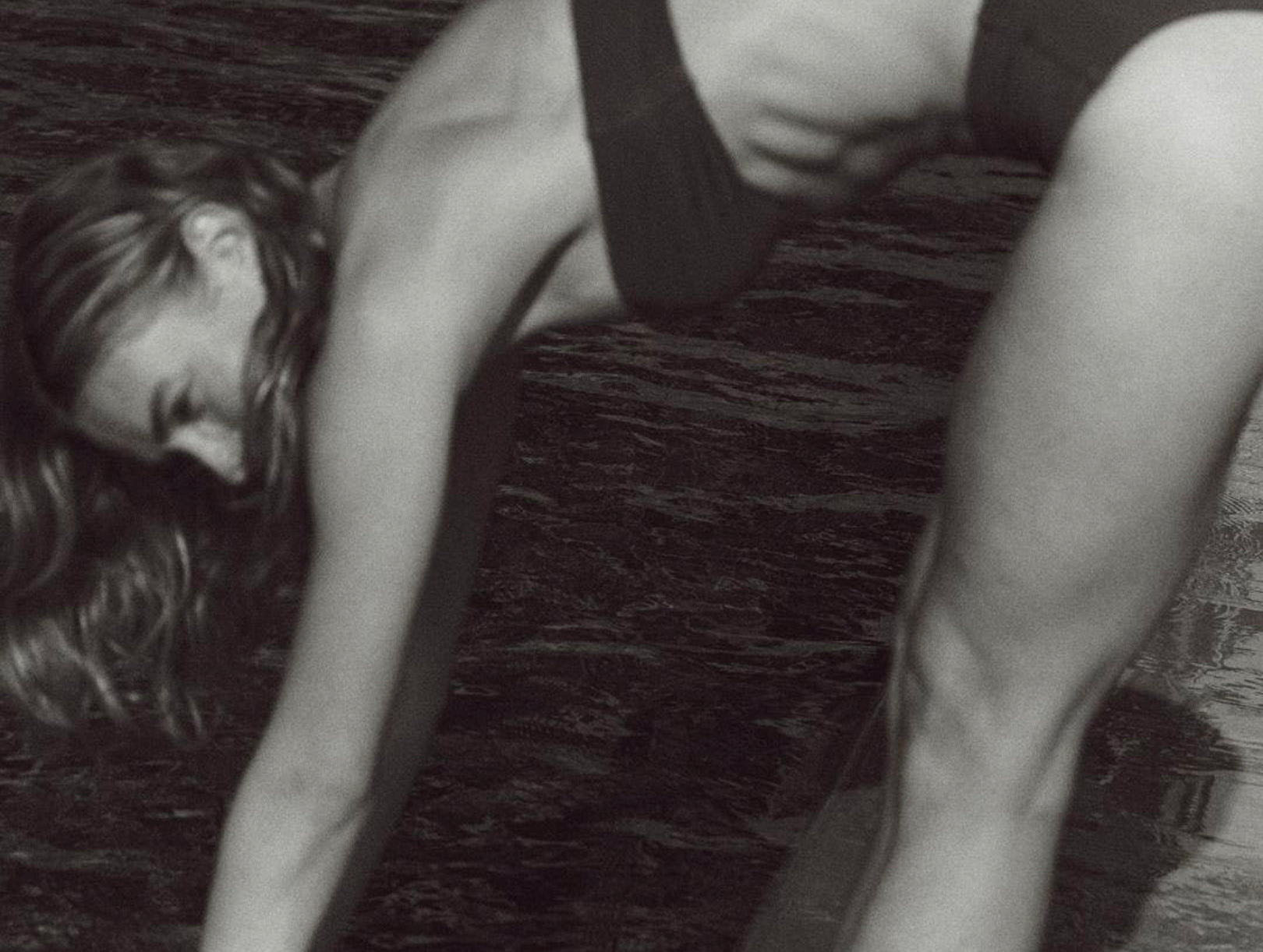 Artistic black and white motion-blurred photograph of person in swimwear creating ethereal movement effect