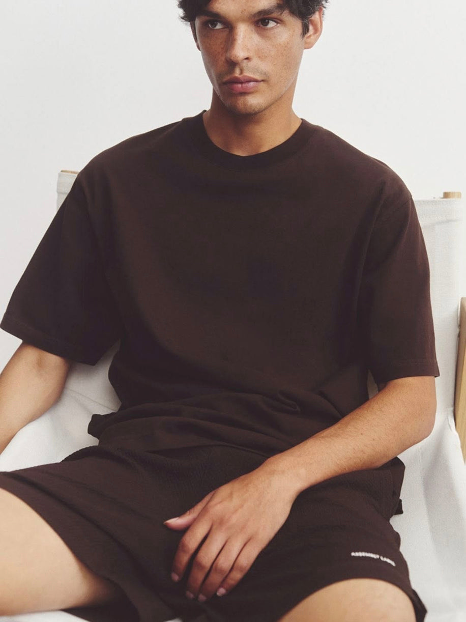 Model wearing oversized chocolate brown t-shirt and matching shorts in minimalist studio setting