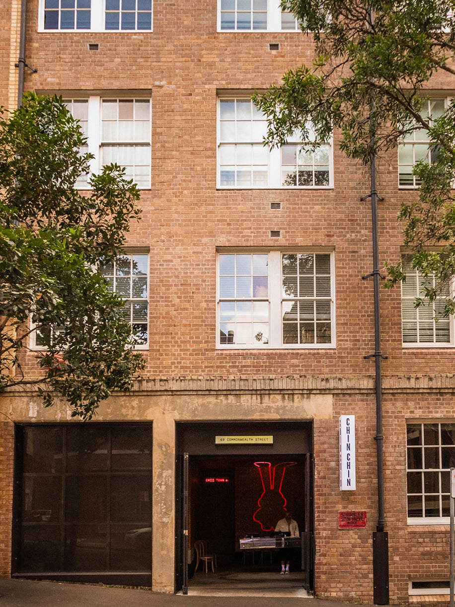 Street view of restaurant entrance featuring red neon rabbit logo above doorway in brick building