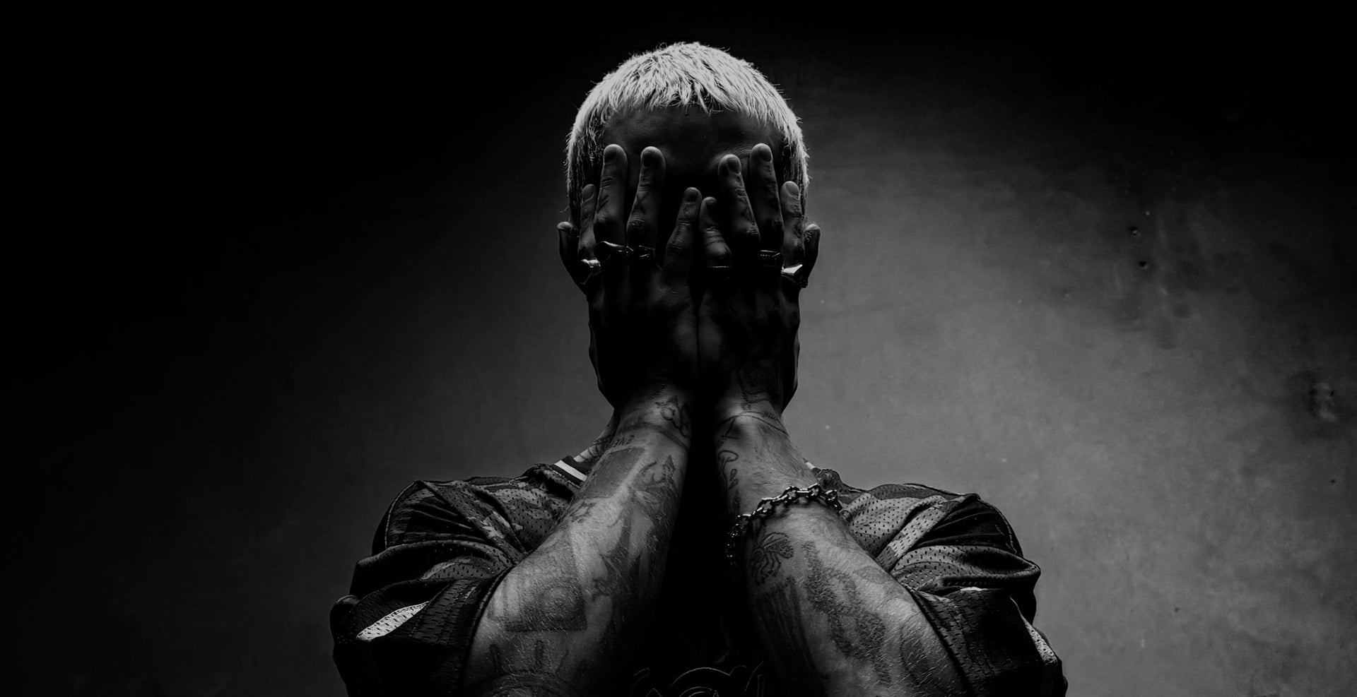 Dramatic portrait of person with hands covering face on dark background