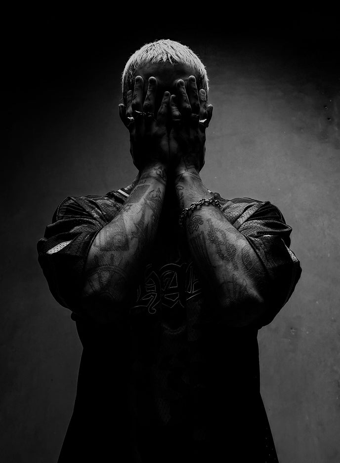 Dramatic portrait of person with hands covering face on dark background