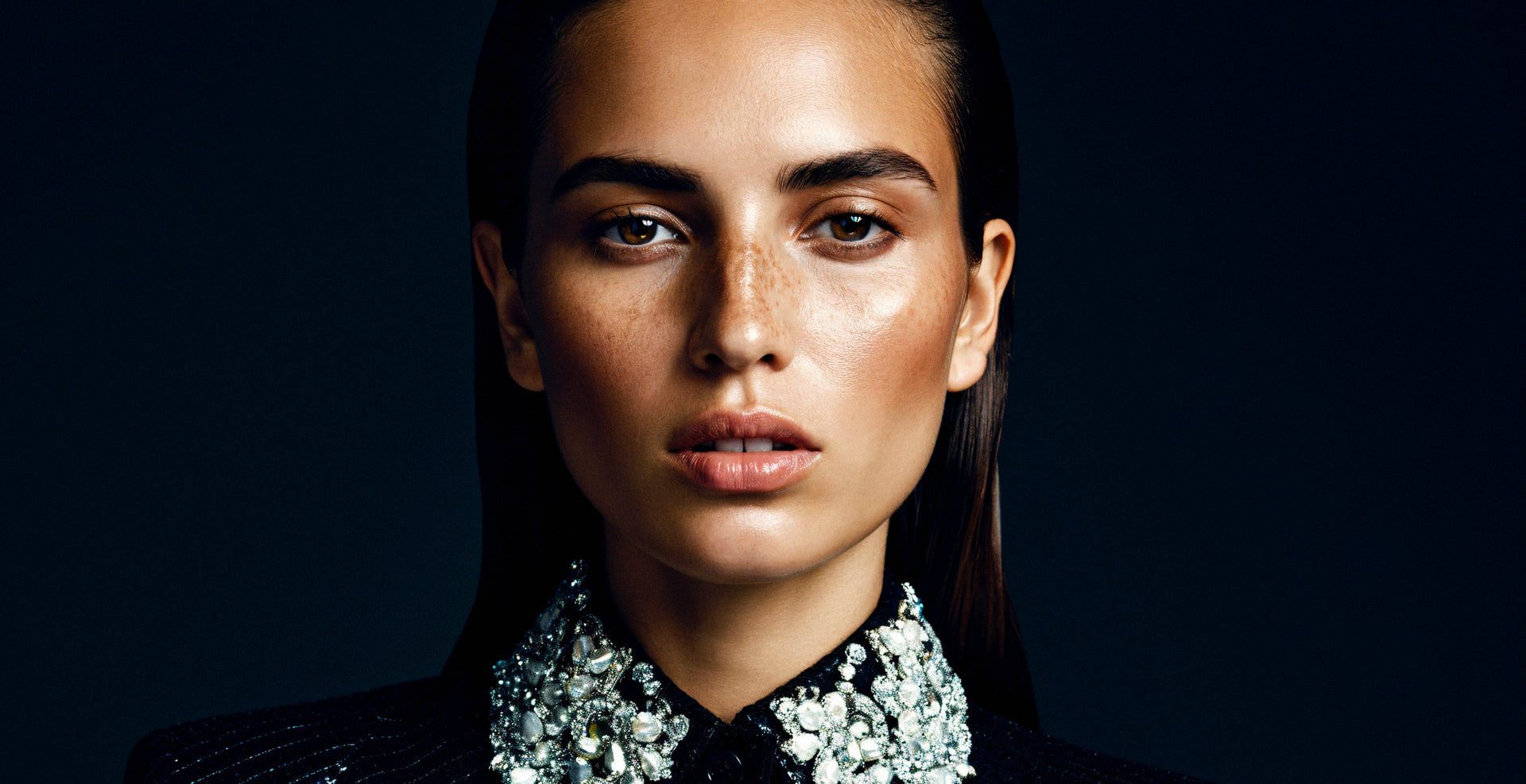 Close-up portrait of a woman wearing a shirt with a bejewelled collar. 