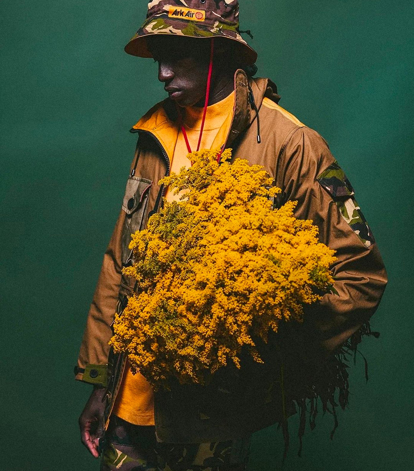 Person holding a large bouquet of yellow flowers against a green background