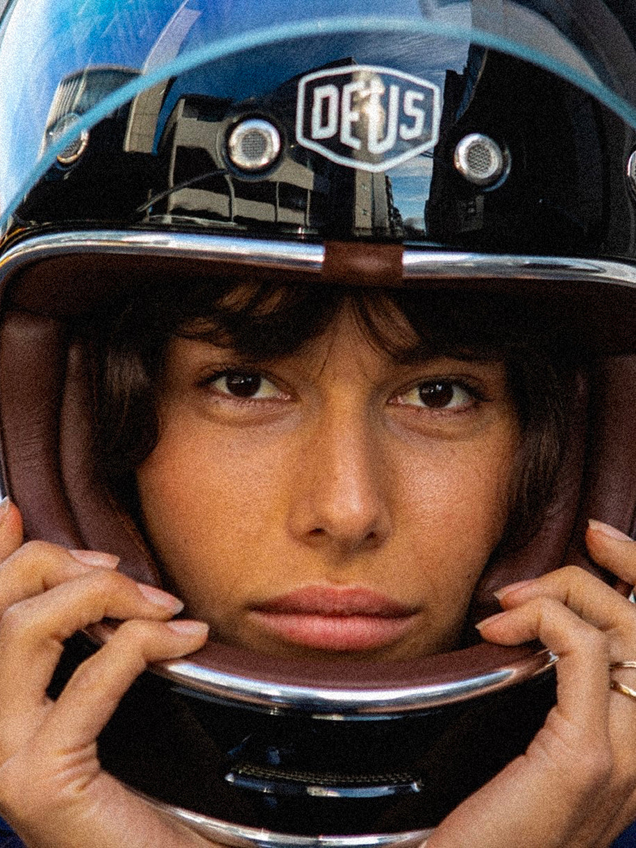 Person wearing a motorcycle helmet with 'Deus' branding