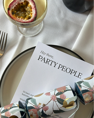 Elegant table setting with invitation card on white plate with passion fruit cocktail and Christmas cracker