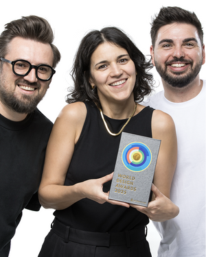 Three team members holding World Shopify Design Award trophy in professional studio portrait on white background wearing black attire