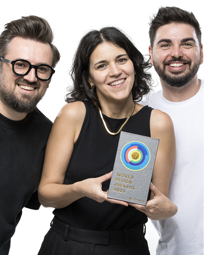 Three team members holding World Shopify Design Award trophy in professional studio portrait on white background wearing black attire