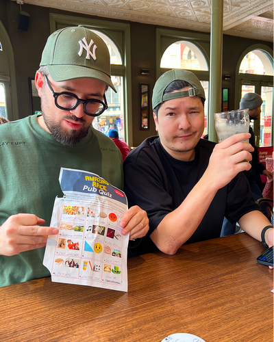 Two people at a Pub Quiz wearing caps