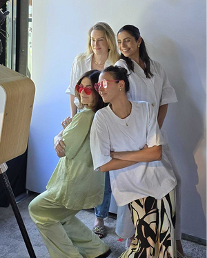Four people in casual studio portrait, two standing, two sitting in front of white backdrop