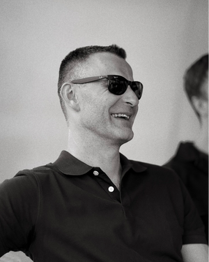 Man wearing sunglasses and a black shirt against a plain background