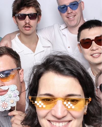 Group photo of five people wearing novelty sunglasses in photo booth