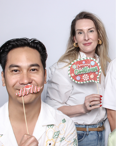 Two people at holiday event holding festive photo booth props