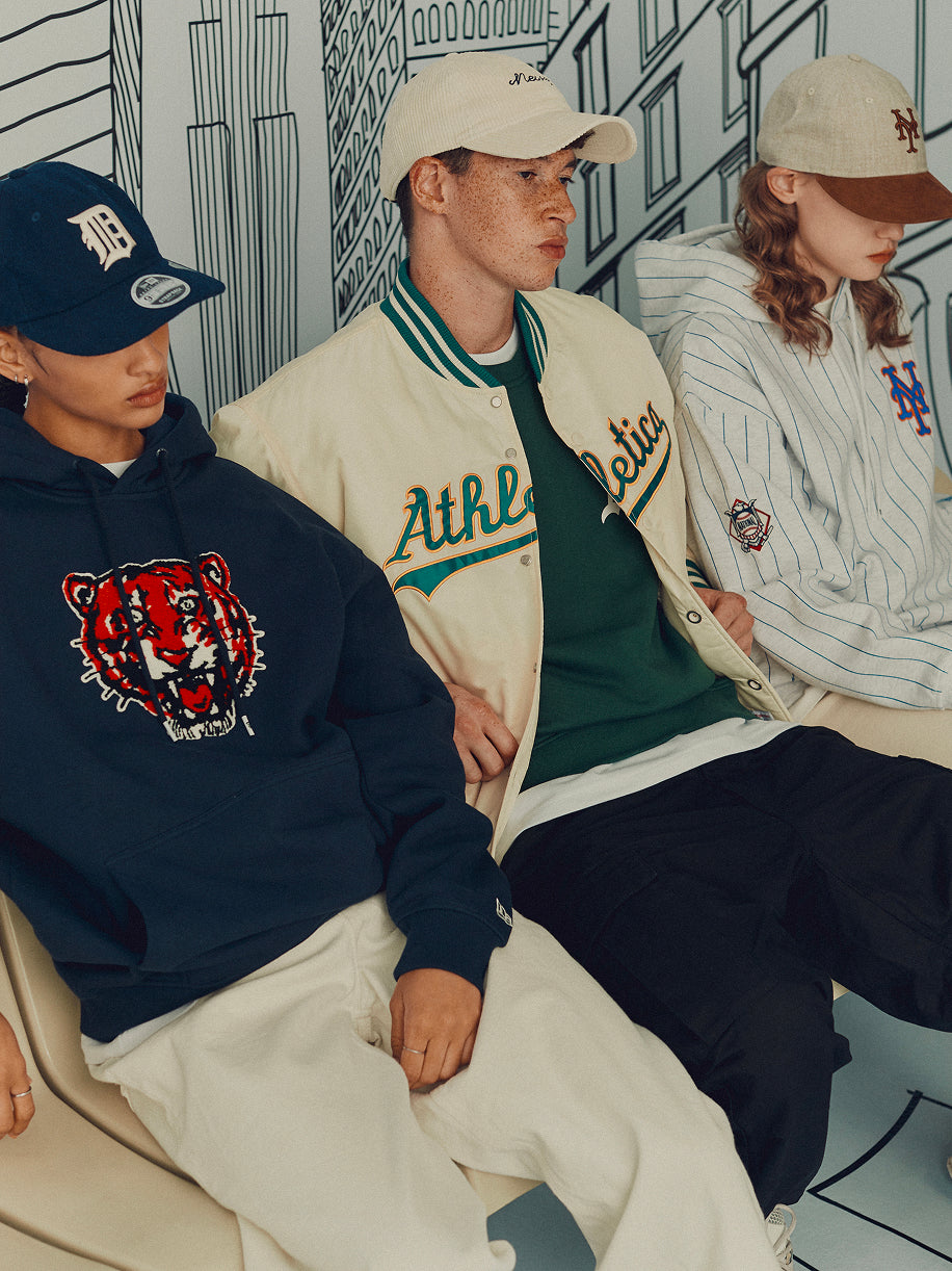 Three people sitting together wearing baseball caps and casual clothing with visible brand logos.