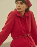 Woman wearing a red jacket with a belt against a neutral background