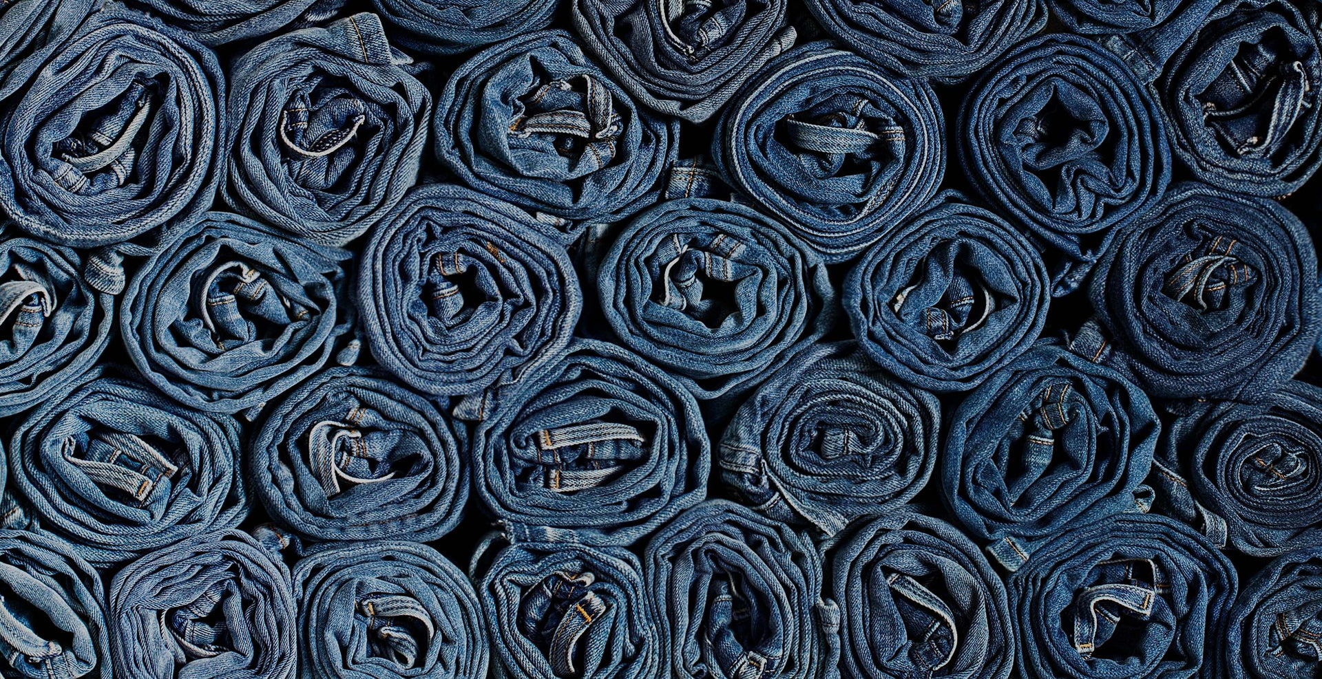 Pattern of rolled up denim jeans in grid formation. 
