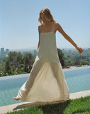 Woman in a long dress standing by a pool with a cityscape in the background
